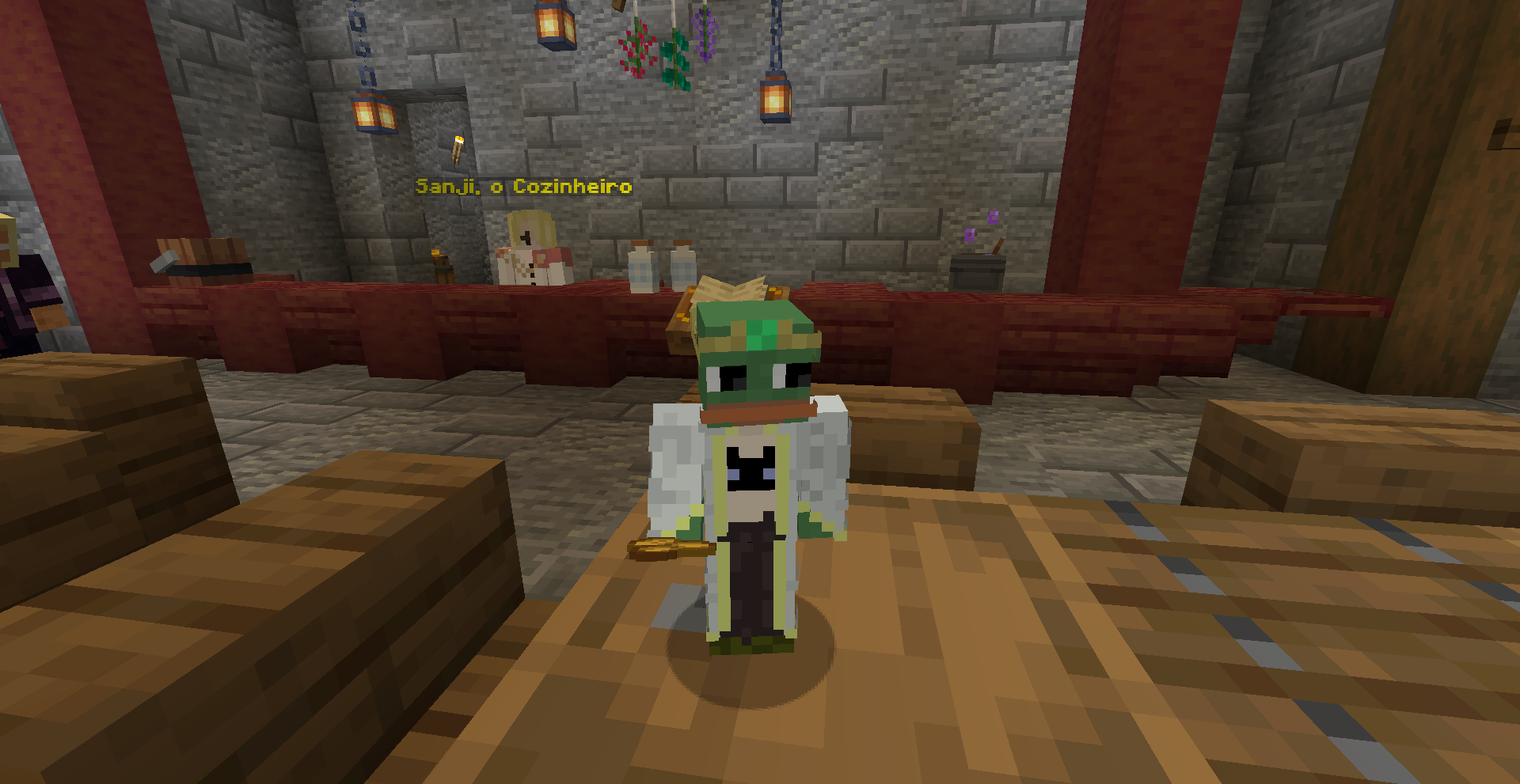 Personagem de capuz verde em forma de sapo, de pé numa cozinha de pedra, diante do balcão onde atende o NPC “Sanji, o Cozinheiro”